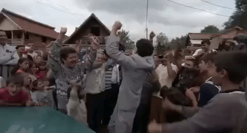An animated gif of Borat surrounded by villagers, all celebrating
